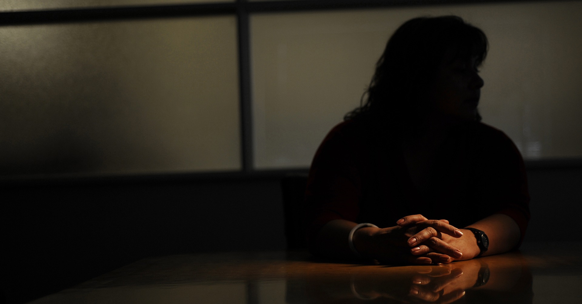 Silhouetted figure of a person seated at a table, highlighting the concept of anonymity in witness protection through Respeecher voice cloning technology