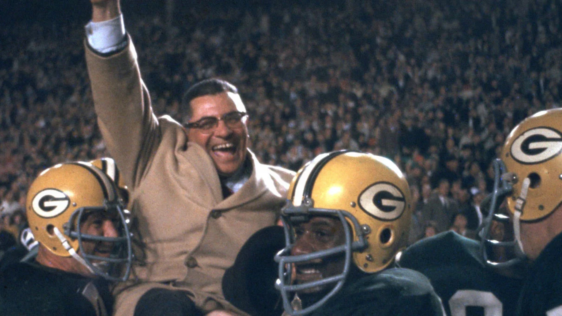 Legendary Green Bay Packers coach Vince Lombardi being carried triumphantly by his players after a victorious game, with the crowd cheering in the background, in a nostalgic scene from the 1960s