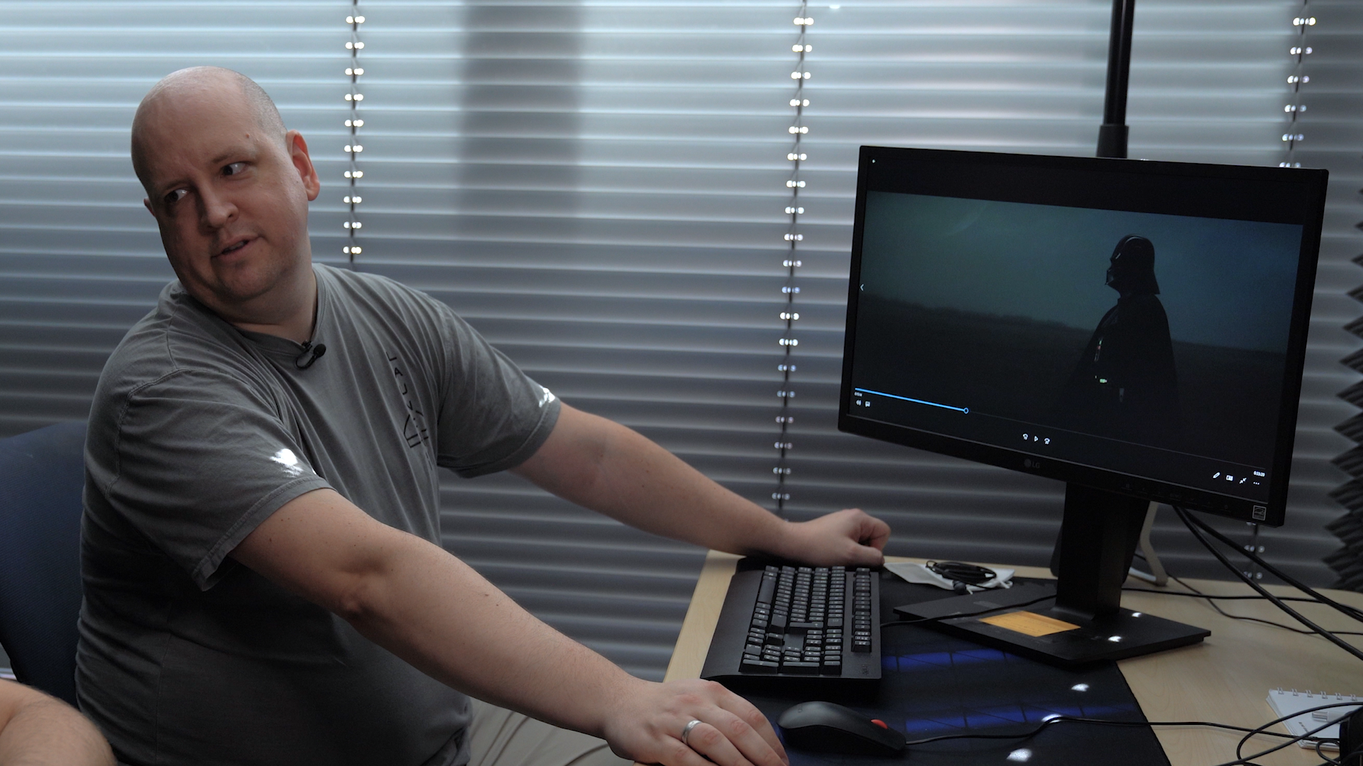 Professional audio engineer in a modern studio setting, reviewing footage of Darth Vader on a computer screen, highlighting advanced voice cloning technology for character dubbing