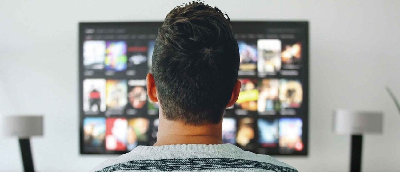 A person from behind looking at a screen filled with diverse media content, symbolizing AI's impact on audio services across various digital platforms.